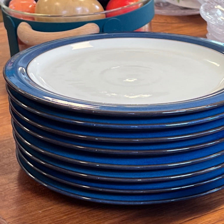 Dessa åtta handgjorda stengodstallrikar i en djupblå glasyr och gråbeige kombinerar klassisk brittisk design med modern hållbarhet – perfekta för både vardag och fest.