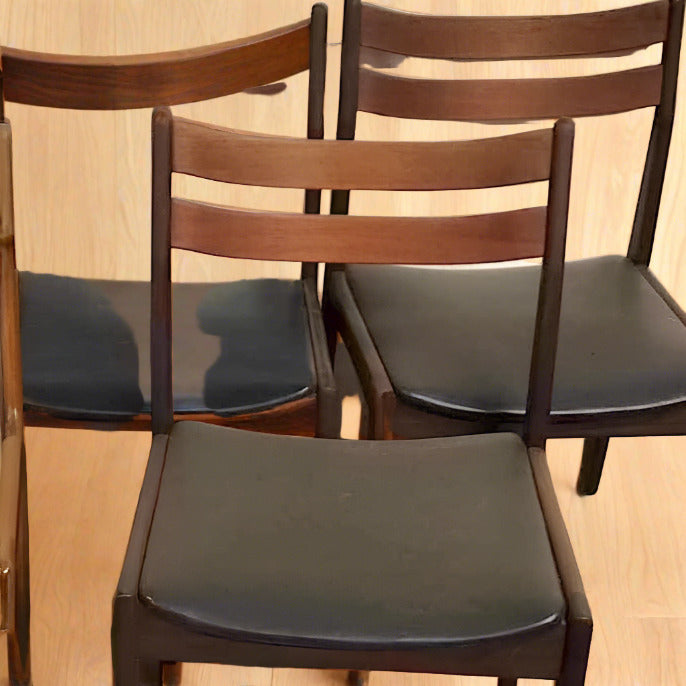 Matrumsstolar i mörkbetsad teak som har tvärslå i ryggen. De tre stolarna har blivit omklädda med ny svart skinnimitation som de också tidigare hade. 