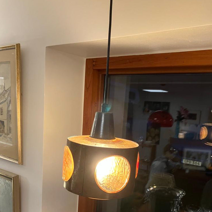Nanny Still's lampa förtrollar med sin konstruktion av koppar och gult glas, vilket skapar en subtil, varm belysning