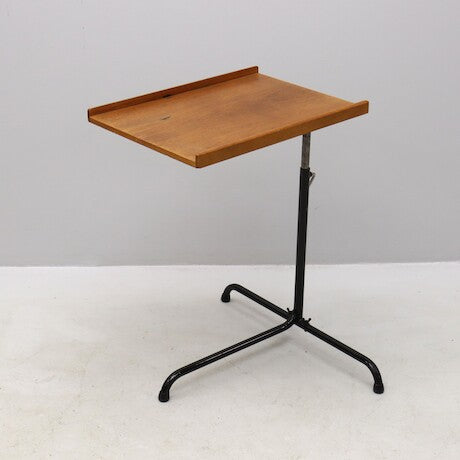 Den vackra träskivan i teak ger ett mjukt och levande uttryck, medan metallställningen – delvis svartlackerad – skapar en elegant kontrast och stabil grund.