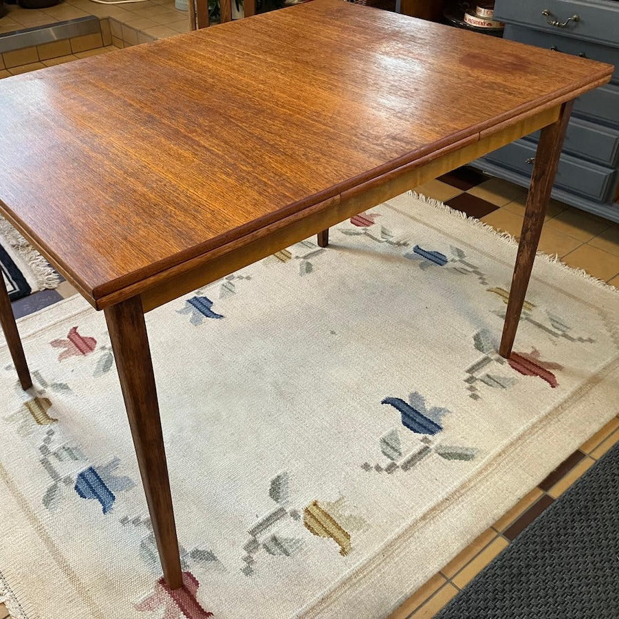 Matbord i mörk  teak med klassisk skandinavisk formgivning från 1950-talet. Bordet har den varma lyster och fina ådring som gjort teak till ett av de mest älskade möbelträslagen från efterkrigstiden.