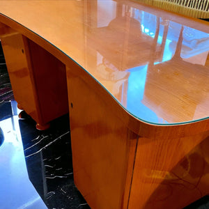 Skrivbord helt i trä med svängd form från 1930–40-talet som är fanerat med alm. 