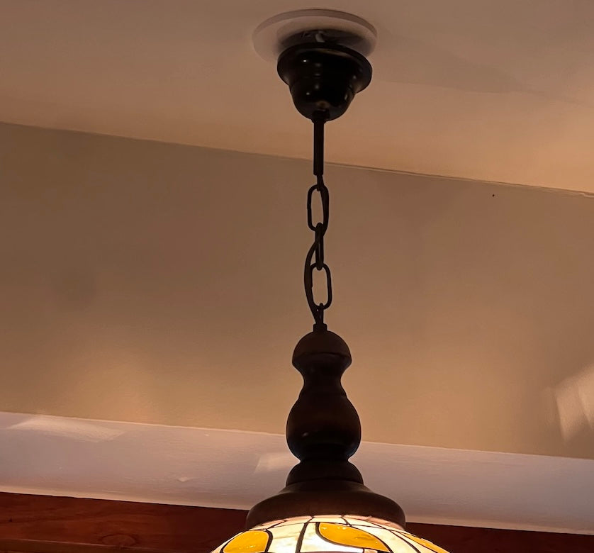Lampan hänger i en mörkt brun kedja med matchande takkopp. Det är en stilfull trädetalj som håller lampan och förstärker den vintagekänsla som gör Tiffany-lampor så älskade.